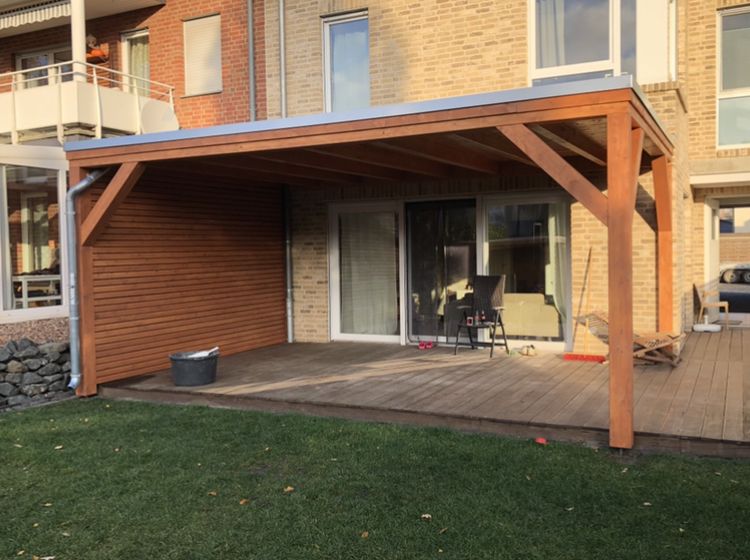 Fertige Terrassenüberdachung aus Holz über einer Holzterrasse